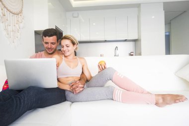Genç çift kanepede oturan ve evde laptop kullanma
