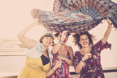 Neşeli bir grup genç kadın eğleniyor ve gülümsüyor açık havada eğlenmek için rüzgarla oynuyor. 