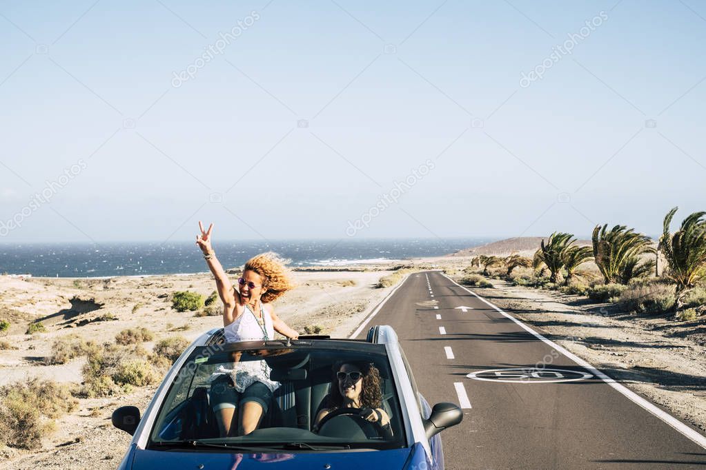 Beautiful traveler young woman staying out of roof of convertible car 