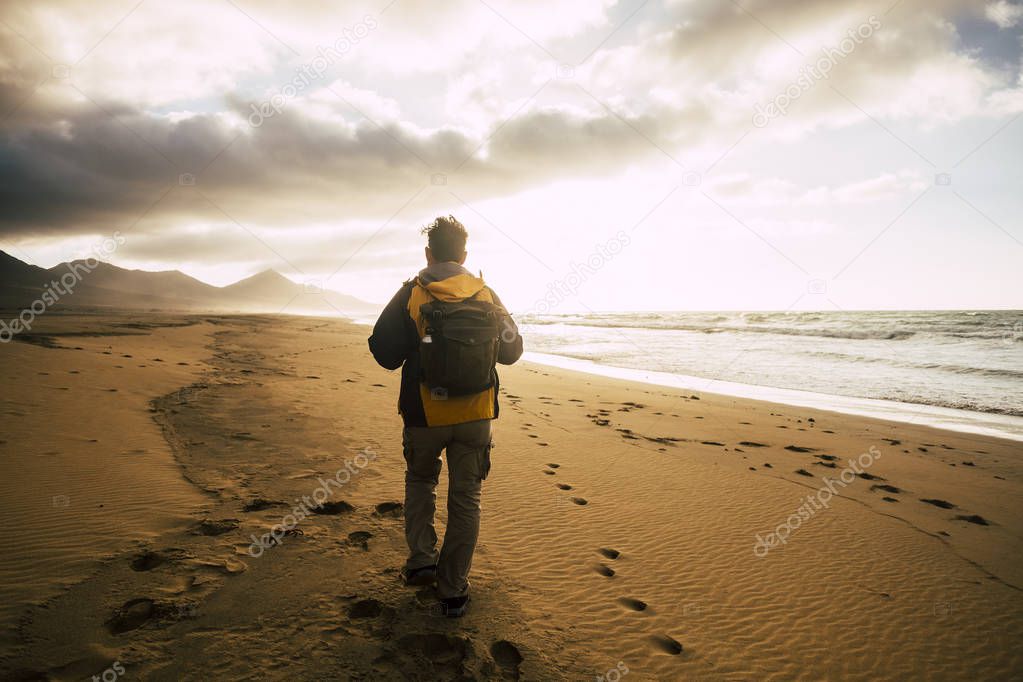 People in back view walking alone with his backpack on the desolation beautiful wild beach for alternative concept of tourism vacation 