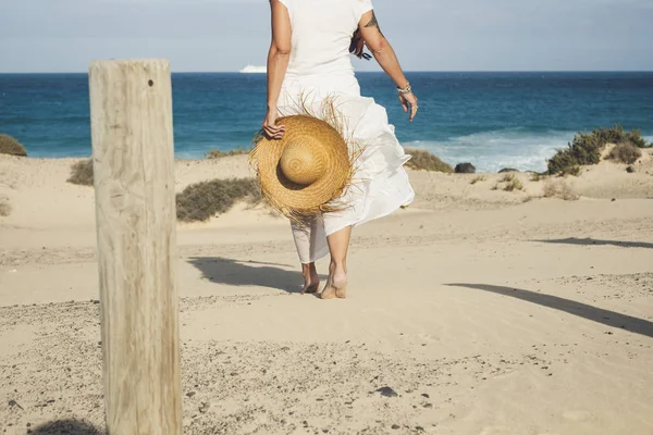 Элегантная Модница Белом Платье Натуральной Шляпе Идет Пляж Барфутом Наслаждаясь — стоковое фото