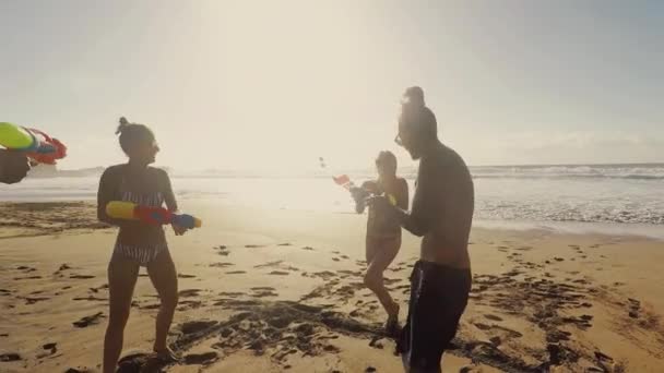 休暇中にビーチで水銃で遊ぶ若者と人々 — ストック動画
