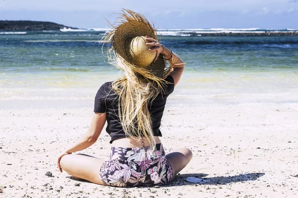 休暇中のビーチで美しいブロンドの若い女性観光客砂を楽しんで自由を感じて 背景に青い海と空 — ストック写真