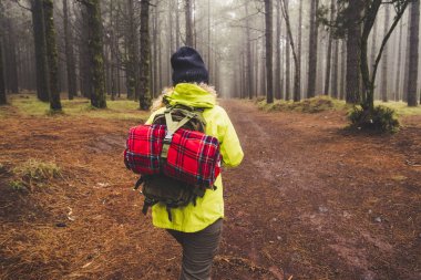 yüksek ağaçları ile ormanda gündüz yürüyen kadın