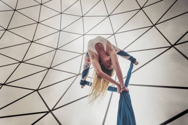 Alternatif bakış açısına göre güzel sarışın kız arka planda beyaz gökyüzü ile hava sirki spor programı egzersizleri yapıyor. 