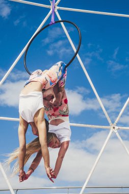 Ters pozisyondaki iki kız akrobatik fitness sergisi yapıyor. Açık havada, sağlıklı alternatif spor yaşam tarzı için dengeli pozisyonlarda daireler çizerek aktivite sergiliyorlar.