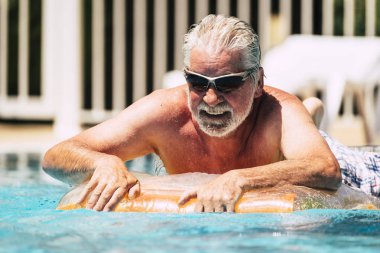 Neşeli beyaz insanlar yaşlı yaşlı adam renkli liloya uzanıp yaz tatilinde yüzme havuzunun keyfini çıkarıyor ya da şehirde dinleniyor.