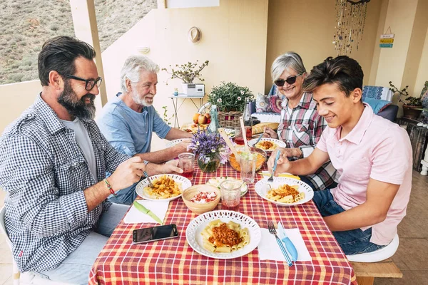 Happy people family concept laugh and have fun together with three different generations ages, grandmother, grandfather, father and young teenager son all together eating at lunch