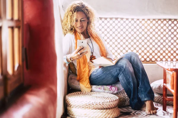 evde oturan ve evde akıllı telefon kullanarak çekici genç kadın 