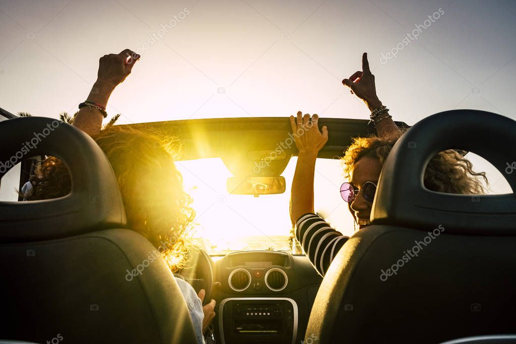 People joy and happy driving and traveling for summer holiday vacation and outdoor leisure activity with convertivle car laughing and dancing like crazy - sunlight in the glass and travel concept