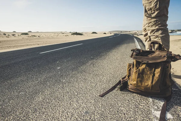 車が旅行を共有するのを待っているトレンディなバックパックで長い道に立っている男のクローズアップ — ストック写真