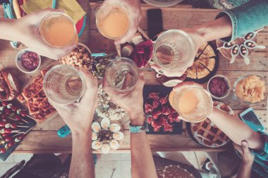 Öğle yemeğinden önce kutlama yapmak için kadeh kaldıran insanlar.