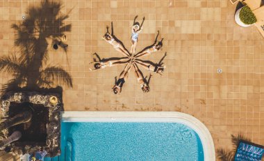 Bir grup kadının dikey üst görüntüsü. Genç arkadaşlar, vücutlarıyla birlikte bir yıldız oluşturuyorlar. Yaz insanları, yaşam tarzı ve arkadaşlığı birlikte tatile çıkarlar.