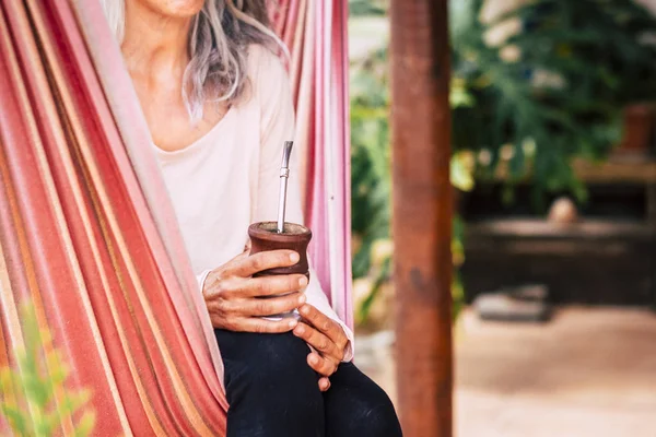 Close up of natural healthy alternative yoga caucasian woman drinking nature tea sitting on an hammock to relax and enjoy outdoor relax leisure activity