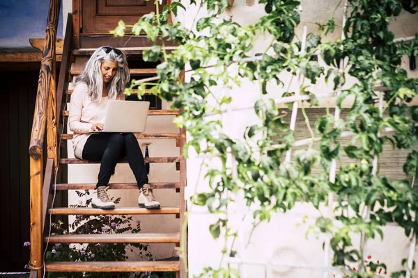 大人の代替多様性の人々のコンセプト白とグレーの長い髪の美しい女性ラップトップコンピュータが家の外の木製の階段に座っている — ストック写真