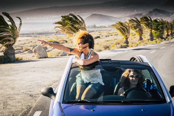Happiness and travel lifestyle people - couple of women adults friends driving and traveling on a blue convertible car
