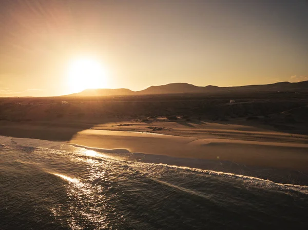 日の出や日没時のビーチと海 背景に山々の後ろに太陽 — ストック写真