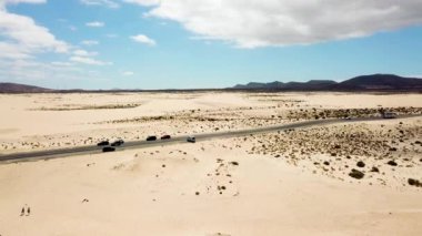 Her iki tarafında kum ve çöl olan siyah düz asfalt yol havadan görünüyor.