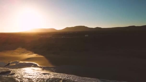 vue aérienne des vagues bleues de l'océan et de la plage de sable jaune au coucher du soleil  