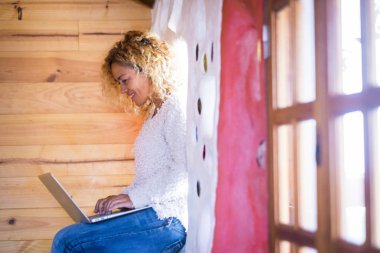 Neşeli güzel kadın renkli çadırı olan bir pencerenin yanında bilgisayar kullanıyor. 