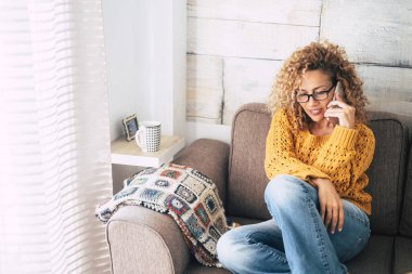 Evde kanepede otururken telefonla konuşan güzel kadın