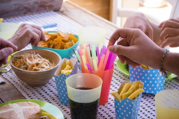close up of hands taking chips and food of the table in a happy party in a house