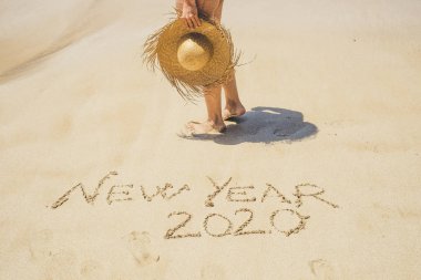 Yeni yıl 2020 kart şablonu ve kumsalda kumların üzerinde kadın bacakları. 