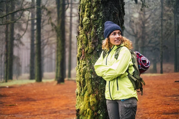 Kışın giyinmiş bir kadın ormanda yürümekten zevk alıyor. 