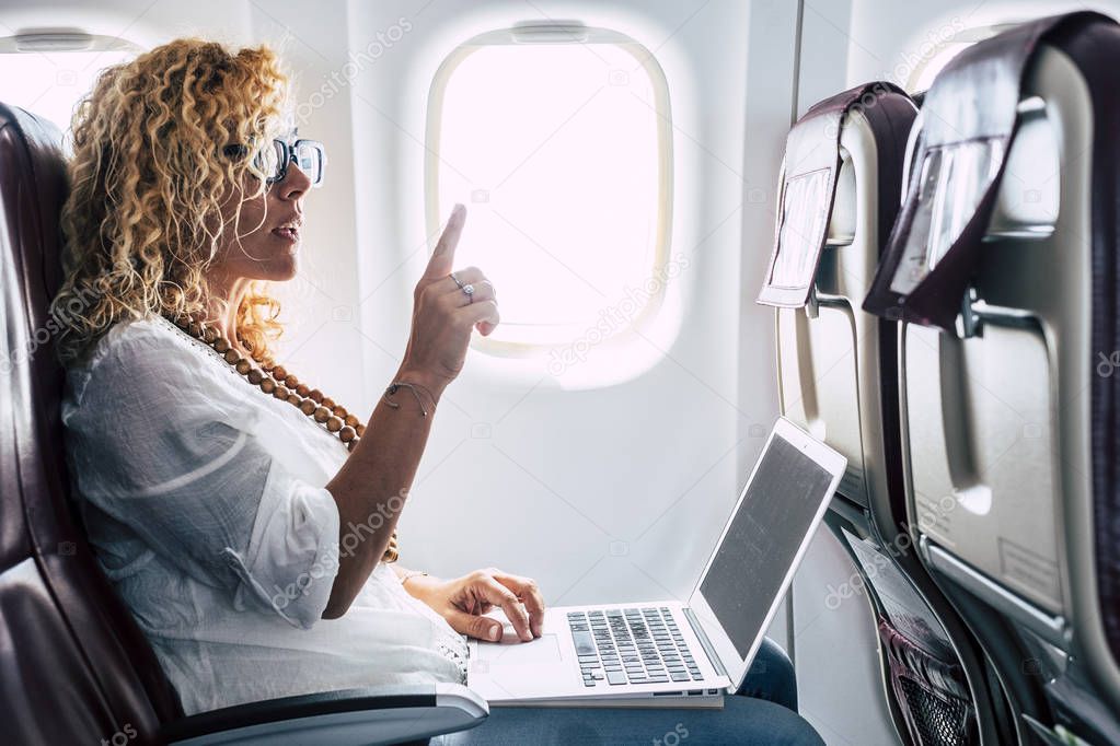 Beautiful female passenger of airplane using personal laptop computer on board