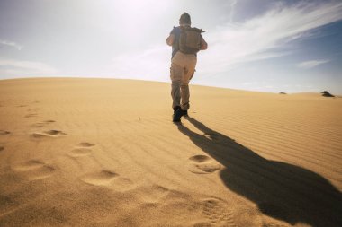 Climate change concept with man walking with backpack in arid clipart