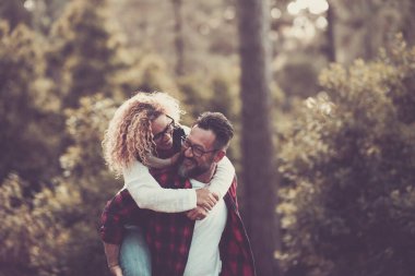 Happy adult caucasian couple in relationship and love play together in the forest wood nature 