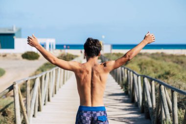 rear view of man standing at beach on sea background 
