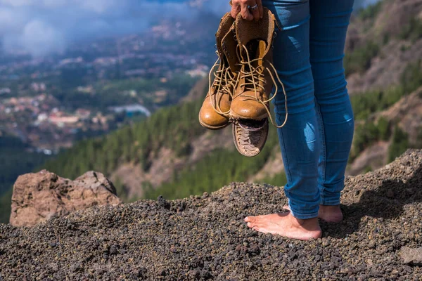 光着脚的女人站在那里 手里拿着破鞋子 看着山顶上的风景 — 图库照片