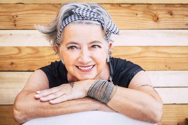 Portrait of cheerful caucasian senior happy woman with wood background - alternative and young old female smile and enjoy - tatooed skin for diversity concept and age - youthful lifestyle