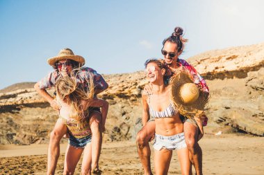 Bir grup mutlu ve neşeli genç insan yaz boyunca plajda birlikte oynuyorlar. 