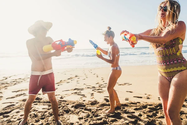 暑假快乐假期人们和一群年轻朋友一起在沙滩上玩水枪的概念 — 图库照片