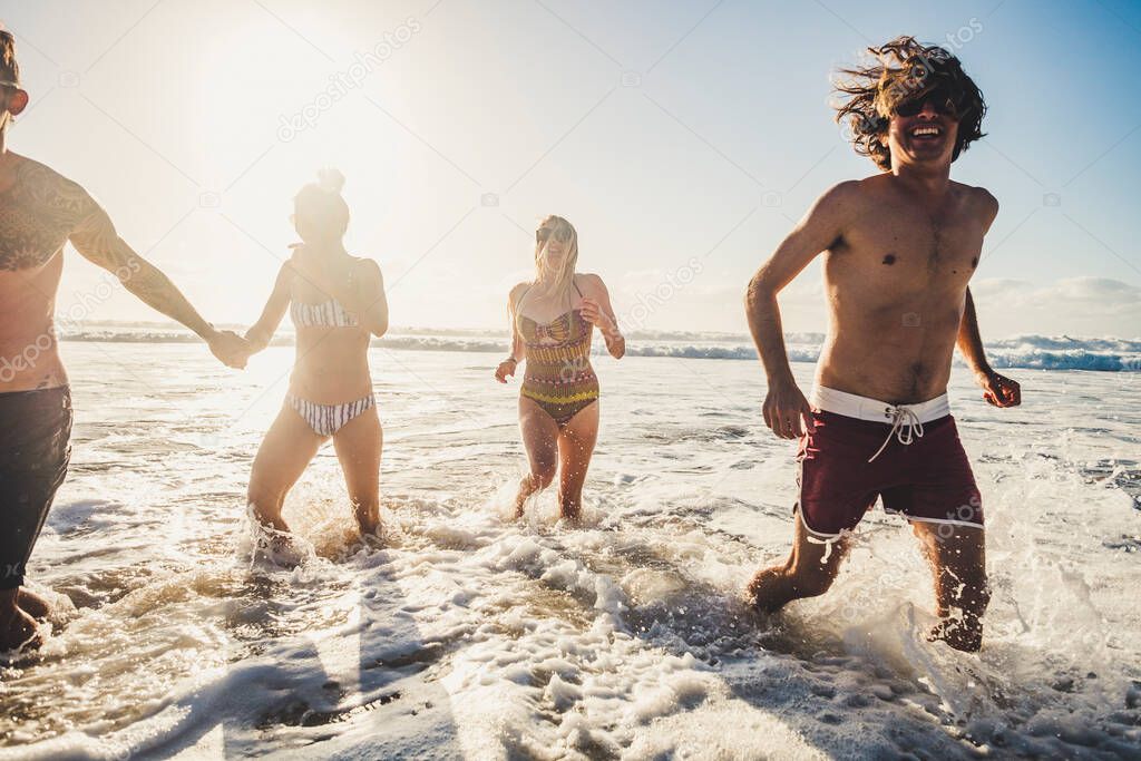 Summer friends and holiday vacation people at the sea playing with water and waves together having a lot of fun 