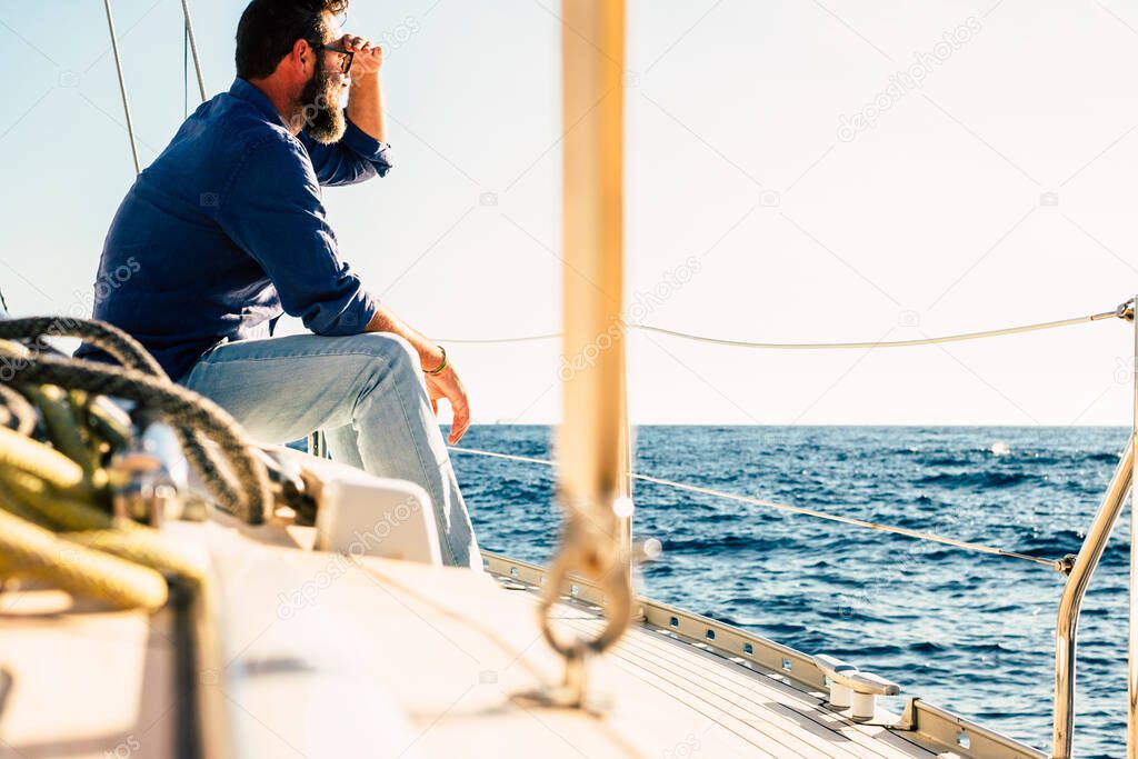 Adult man enjoy outdoor leisure activity sit down on a sail boat looking blue ocean and sky 
