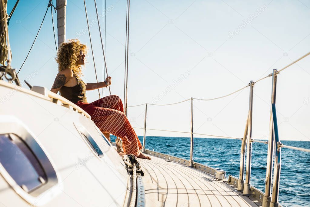 Young beautiful girl lay down and relax on a sail boat enjoying silence and nature - outdoor summer leisure activity during holiday vacation on yacth - travel people and ocean
