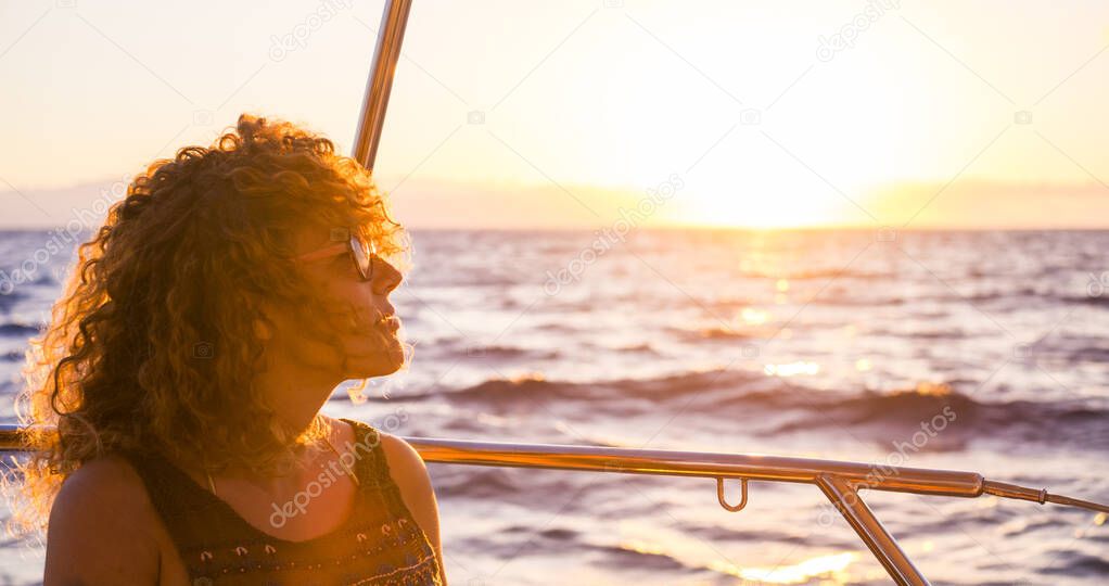 Portrait of a beautiful adult woman enjoying the sunset on a boat, travel and freedom concept for young people 