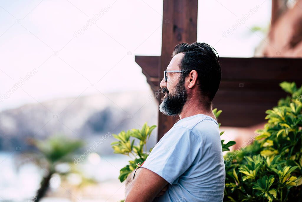 Man with beard portrait looking in front of him, home garden defocuses background