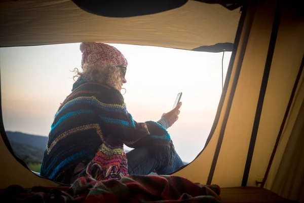 現代の旅行の女性は野生のテントの外でインターネット接続と携帯電話を使用します — ストック写真