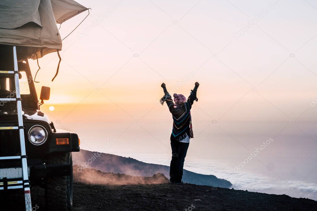 Happy joy people travel with car and tent roof in wild places enjoying the sunset on the top of a mountain
