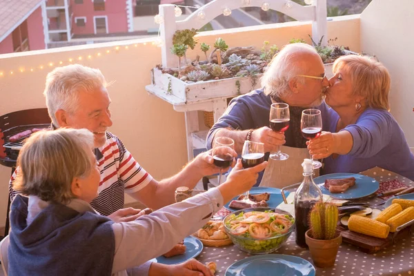 Group of happy senior old people have fun together during lunch or dinner at home in outdoor terrace