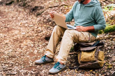 Dijital göçebe ve akıllı çalışma konsepti yaşam tarzı tanınmayan bir adam açık hava parkında, bilgisayarın başında çalışıyor. 