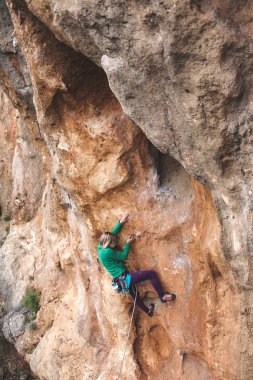 Bir kadın rock tırmanıyor. Doğada tırmanma. Fitness açık havada. Aktif yaşam tarzı. Ekstrem Sporlar. Doğal bir rahatlama atlet trenlerde.