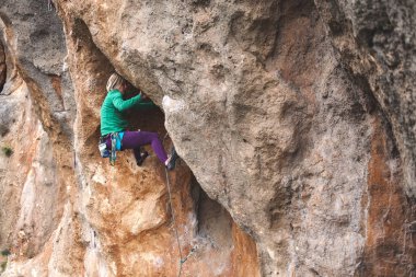 Bir kaya tırmanışçısı. Kız bir tırmanış yapıyor. Doğada spor. Açık havada aktif yaşam tarzı ve spor. Aşırı bir hobi. Cesur kadın..