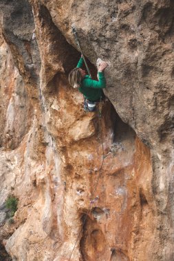 Bir kadın rock tırmanıyor. Doğada tırmanma. Fitness açık havada. Aktif yaşam tarzı. Ekstrem Sporlar. Doğal bir rahatlama atlet trenlerde.