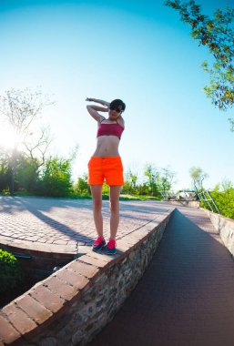 Bir kadın çalışmaları yapıyor. Şehir Parkı eğitimde bir kızdır. Sabah ısıt. Meditasyon doğada. Yoga ve germe.