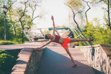 Bir kadın bir şehir parkında germe yapıyor. Sabah eğitim doğada. Yoga pratik. Fitness. Koşu önce kız ısıtır.